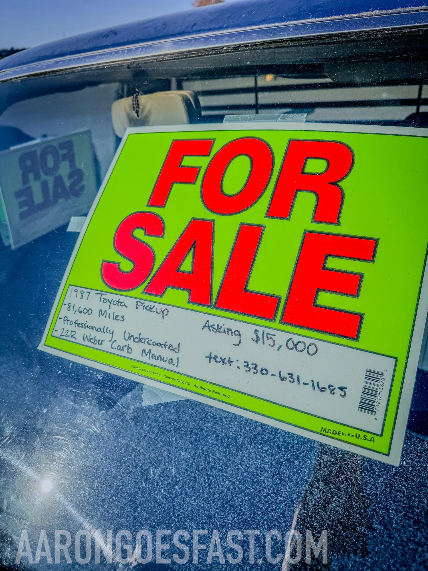 Neon green For Sale sign in the windshield listing a 1987 Toyota Pickup, 81,600 miles, professionally undercoated, 22R Weber carb manual, asking 15,000 dollars