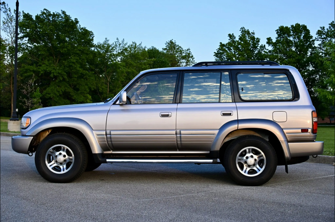 Side profile of a Champagne Pearl 1997 Lexus LX450 with a roof rack