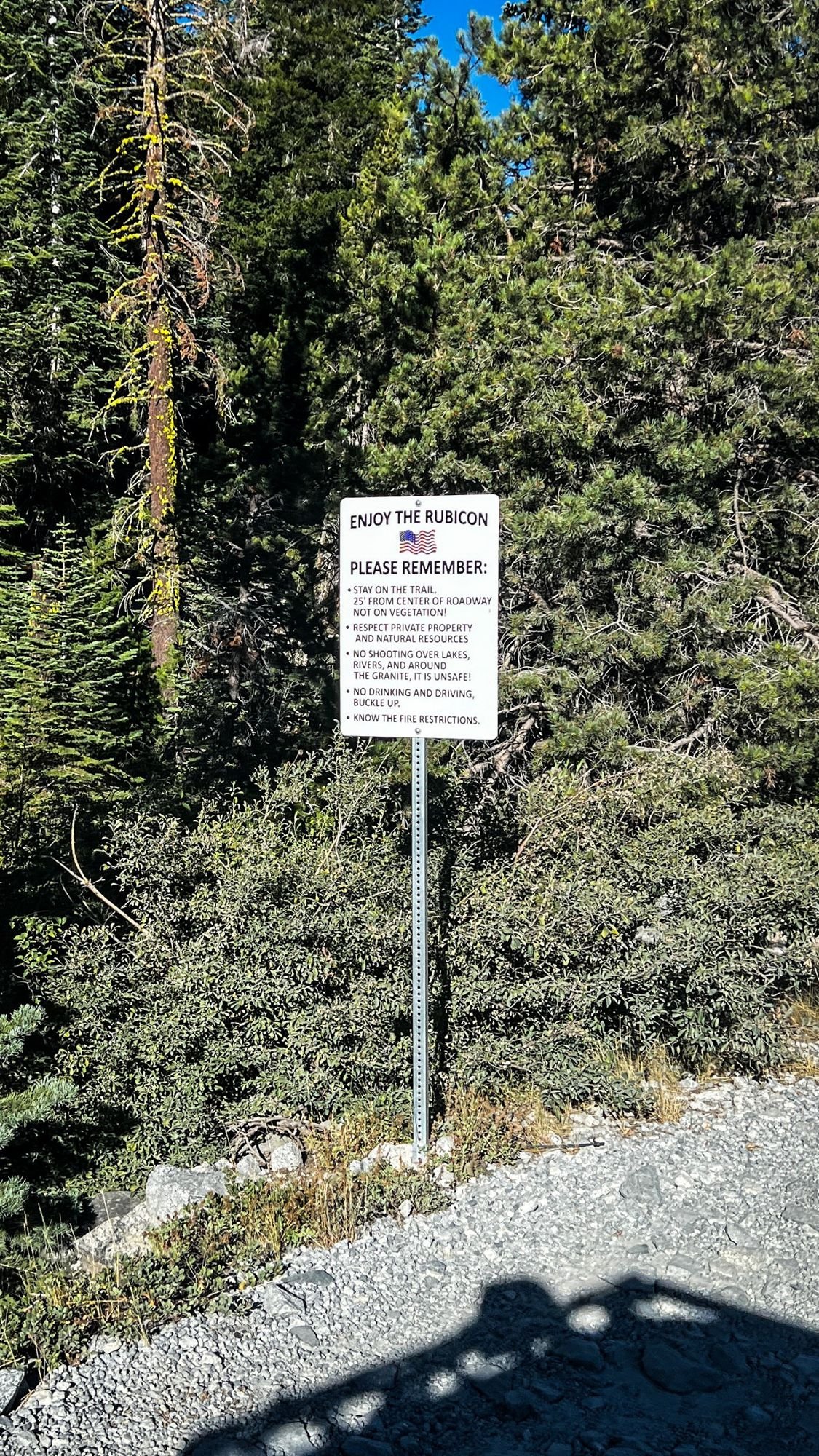White Enjoy the Rubicon trail rules sign on a post in the trees on the Rubicon Trail in California during Rubithon 2022