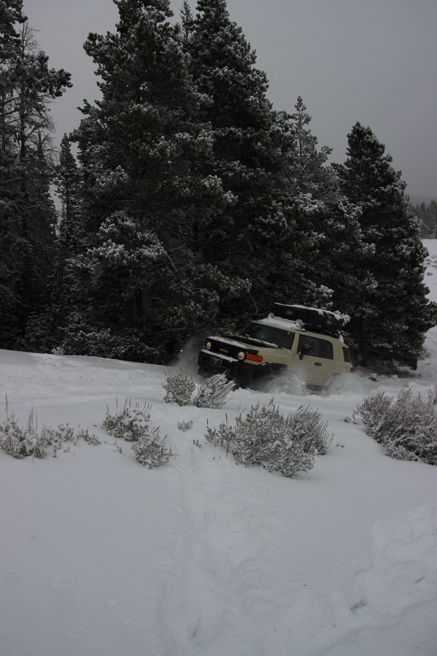 Toyota FJ Cruiser throwing snow spray as it pushes through deep snow during a December snow wheeling run in Montana