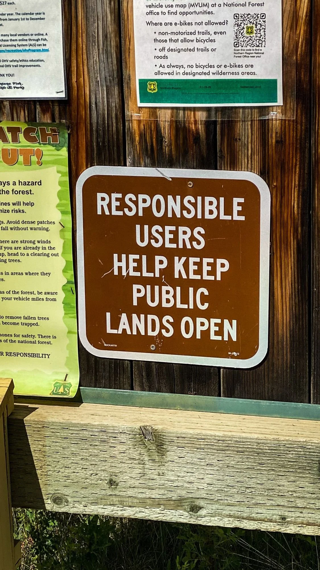 Wooden trailhead kiosk with a brown sign reading Responsible Users Help Keep Public Lands Open on the Middle Fork Judith River road in the Little Belt Mountains, Montana