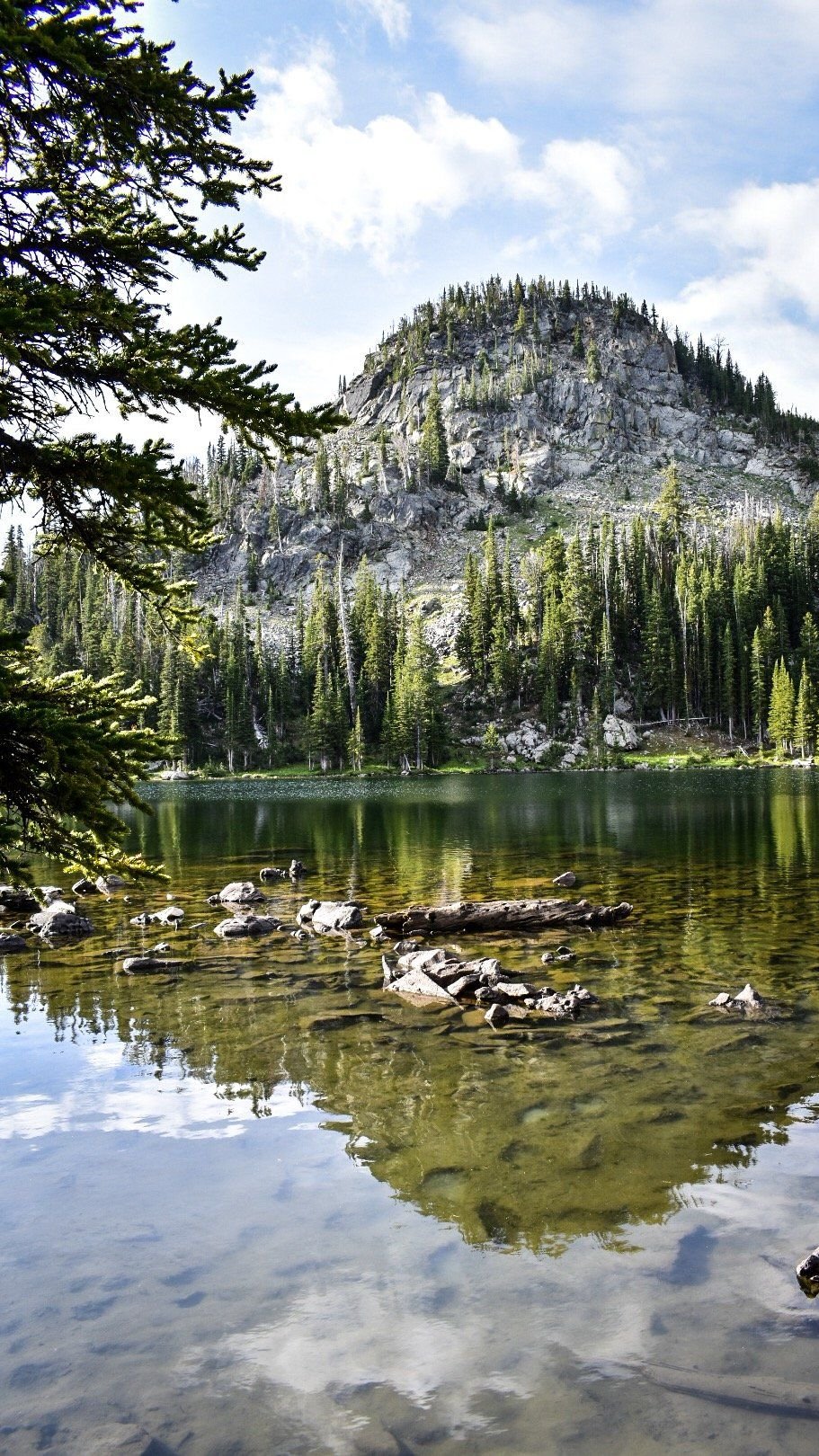 Granite peak and forest reflected in a still mountain lake on the North Meadow Creek trail to McKelvey Lake in the Tobacco Root Mountains, Montana