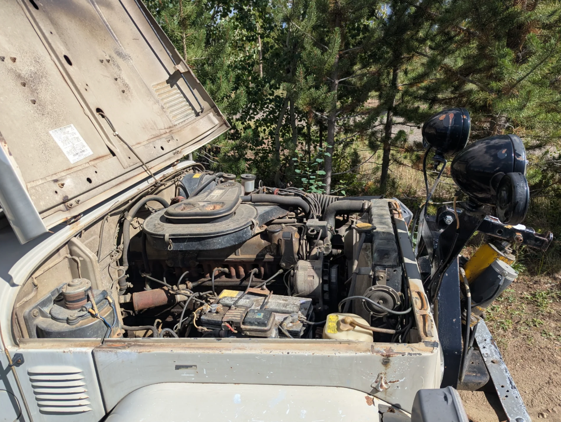 Engine bay of the beige 1977 Toyota FJ40 with the 2F inline-six and auxiliary lights