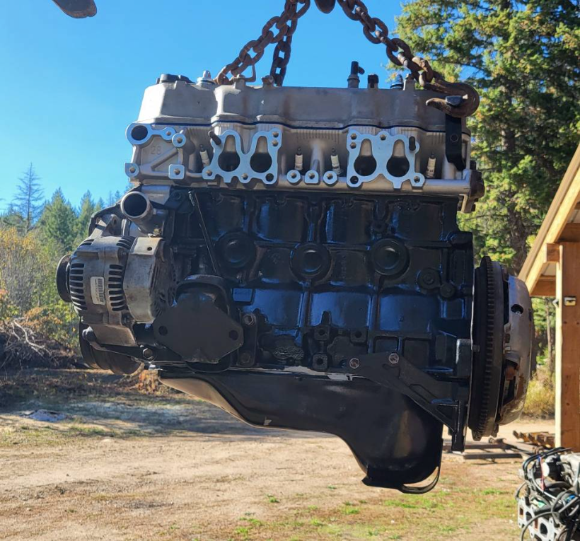 Rebuilt Toyota four-cylinder engine hanging from a chain hoist