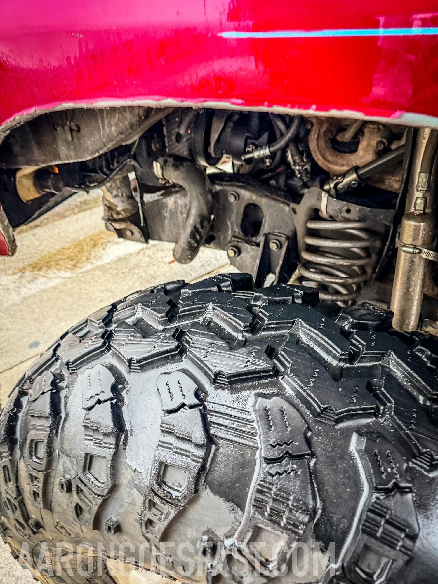 Close-up of tire and suspension underneath the red Ford