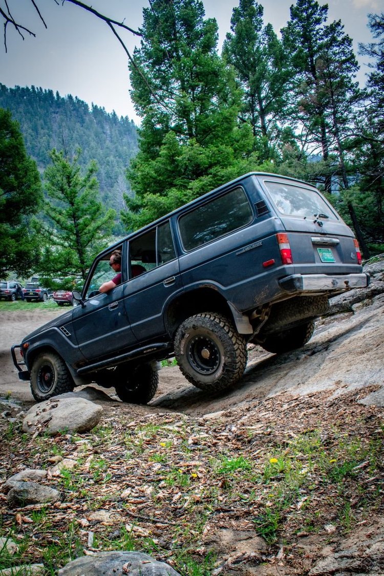 A 60 Series Land Cruiser leaning hard across a tilted rock slab at Ringing Rocks.