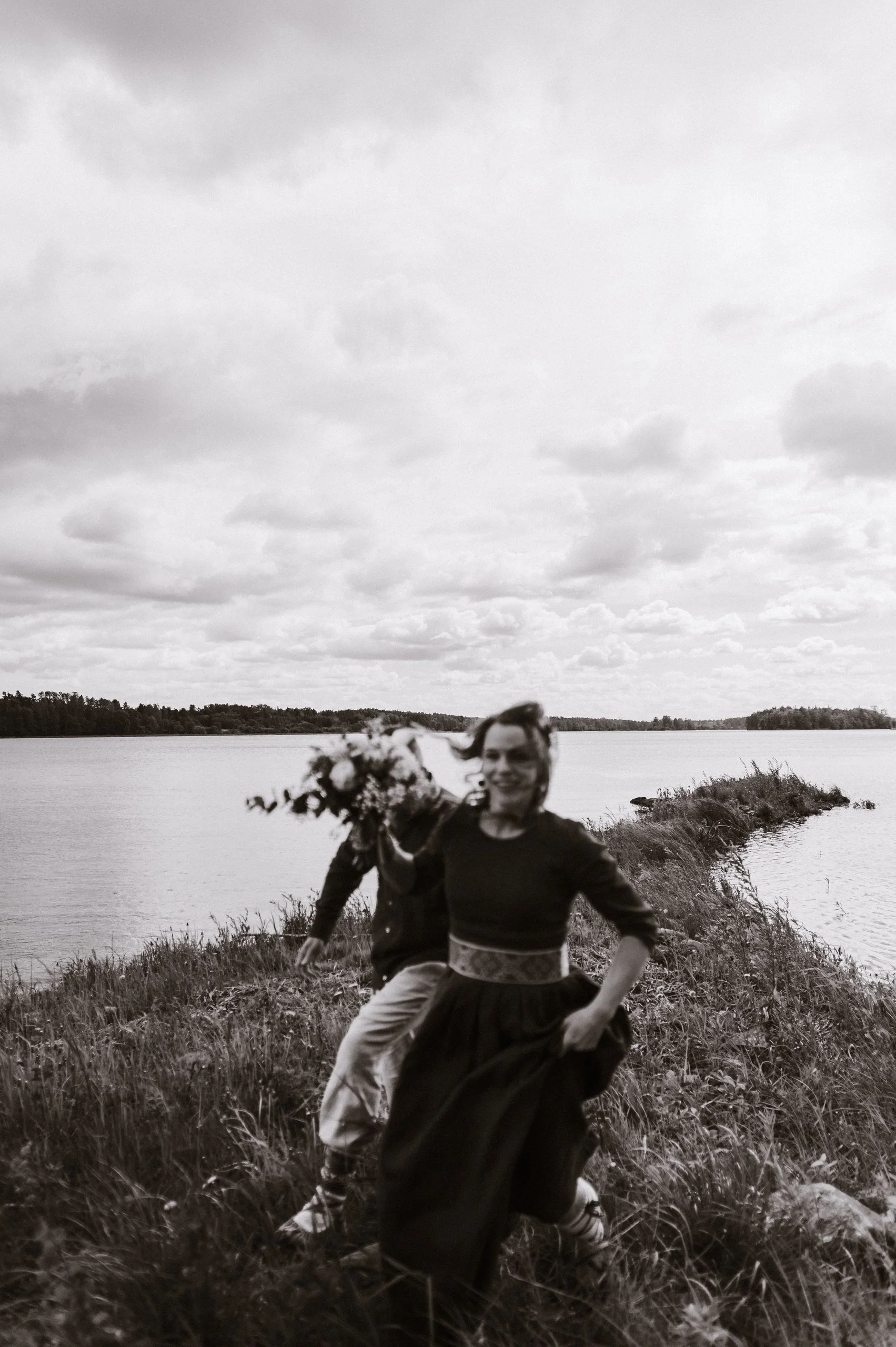 Pāris skrien pa šauru zemes strēli starp ūdeņiem. Melnbalta fotogrāfija.