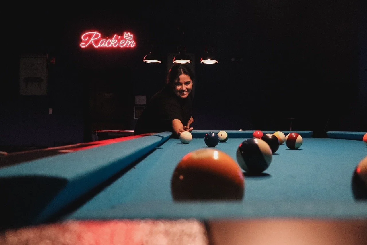 Player lining up a shot at a billiards table under the neon Rack 'Em sign at Silver Stone Castle, Swansea, MA