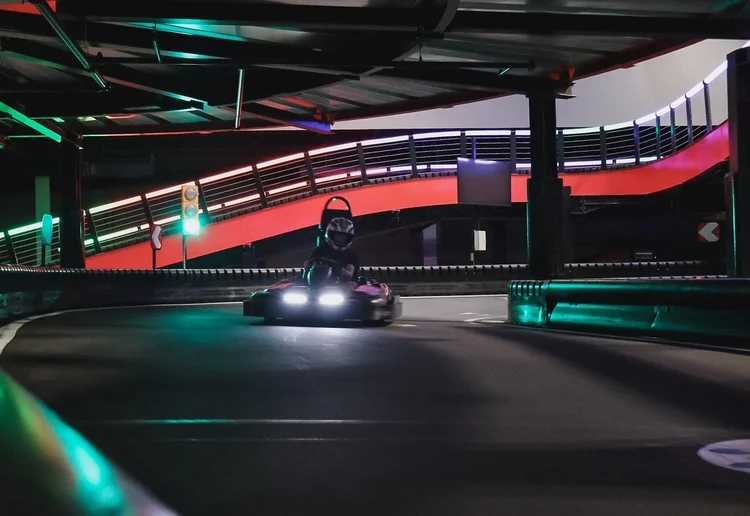 Electric go-kart rounding a banked turn on the indoor multi-level track at Silver Stone Castle, Swansea, MA