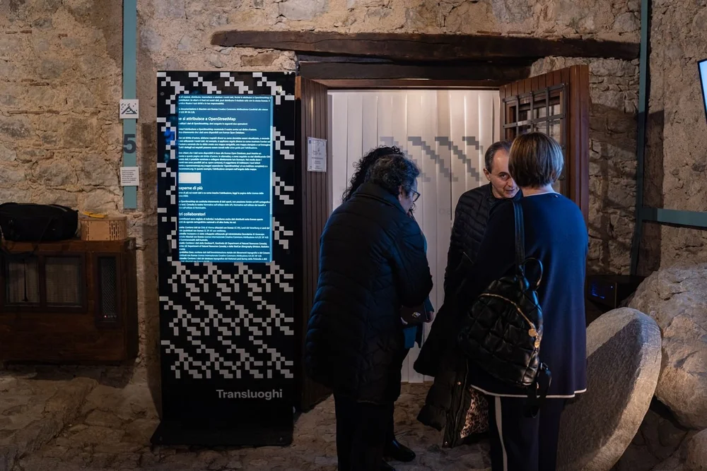 Visitatori davanti alla porta del frantoio, accanto al totem con lo schermo verticale