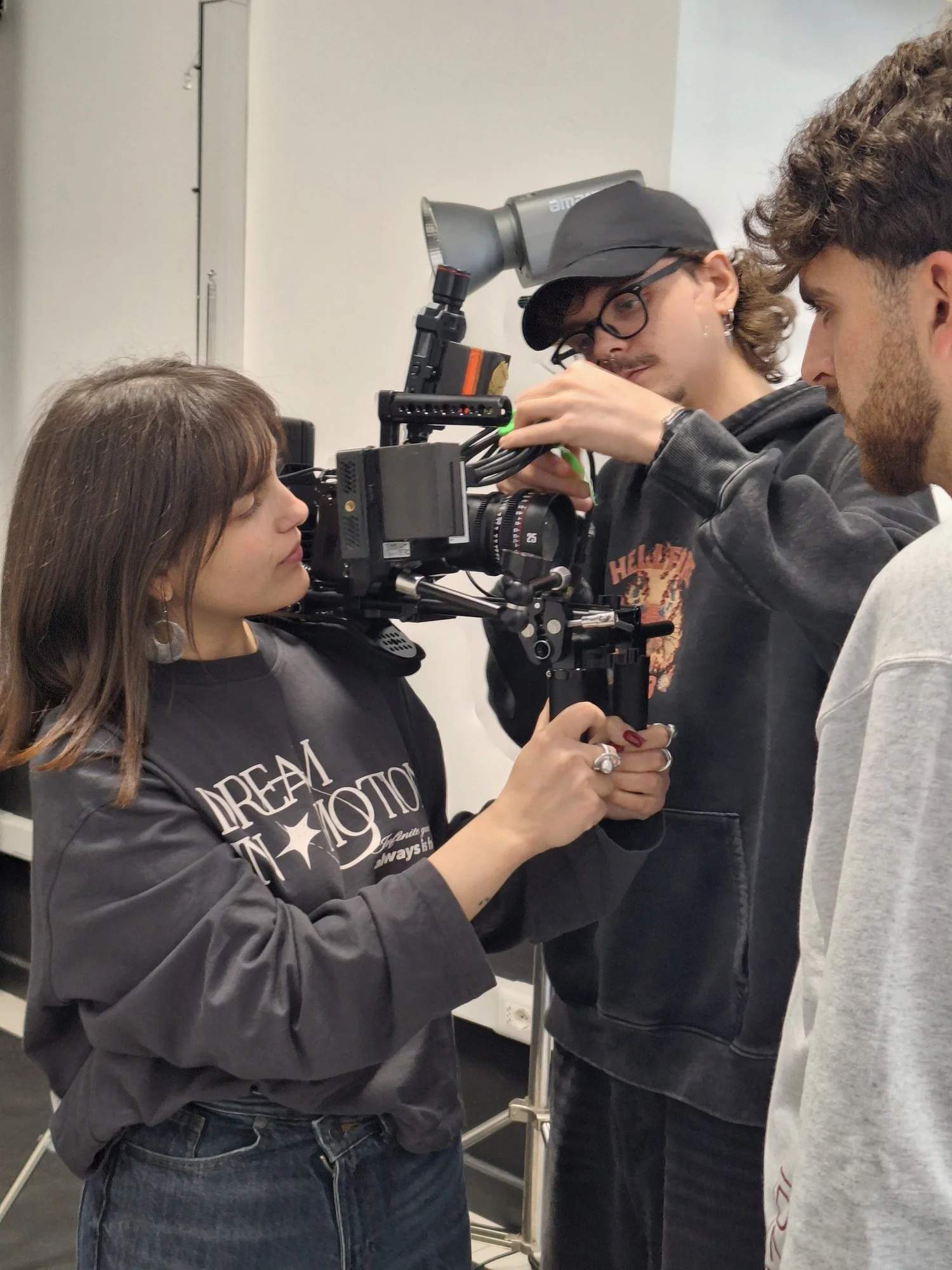 Allieva con la macchina da presa in spalla durante un'esercitazione in studio