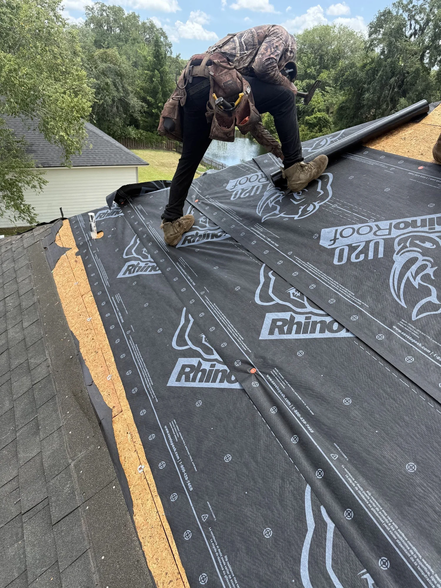 Roofer installing synthetic underlayment over new roof decking