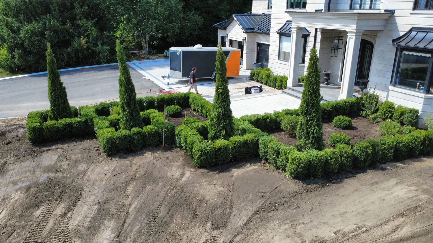 Aerial view of new boxwood and cedar garden beds in front of a large home