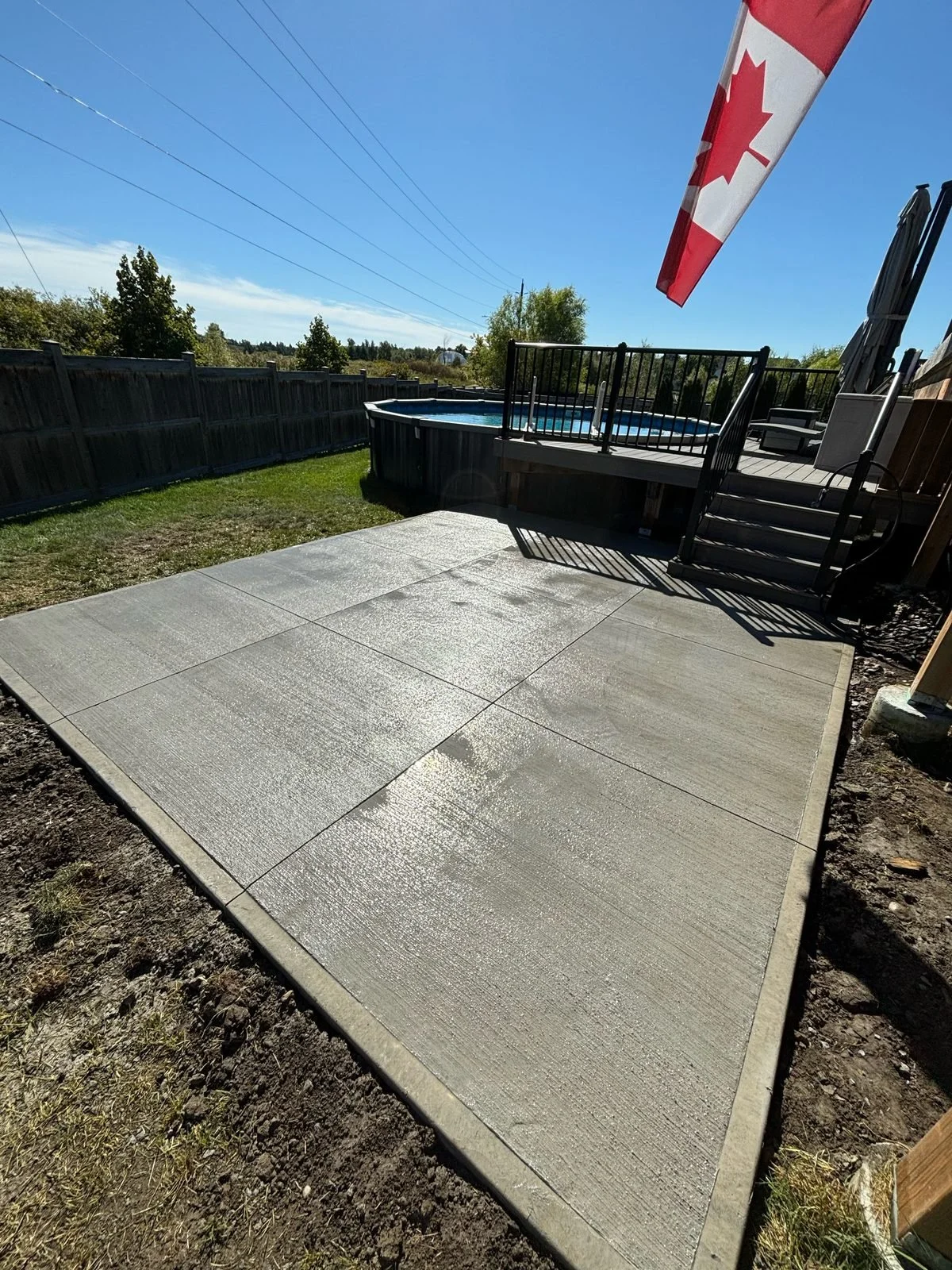 Broom-finish concrete patio slab with saw-cut joints beside a pool deck