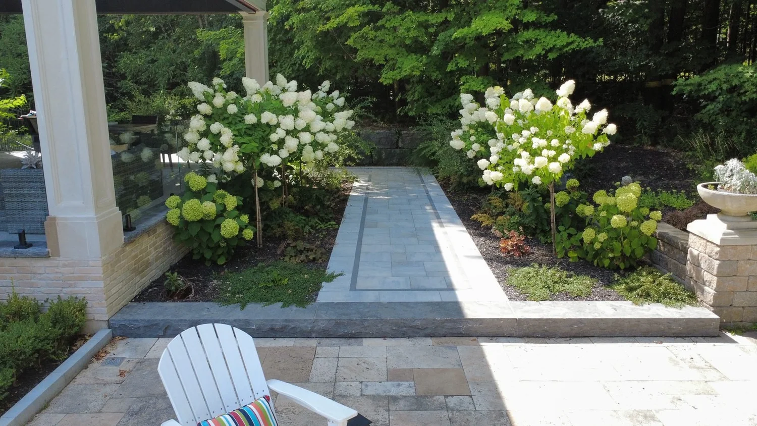 Interlock walkway lined with hydrangeas, leading to stone steps