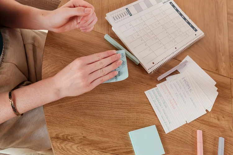Hands using flashcards beside a planner on a wooden table
