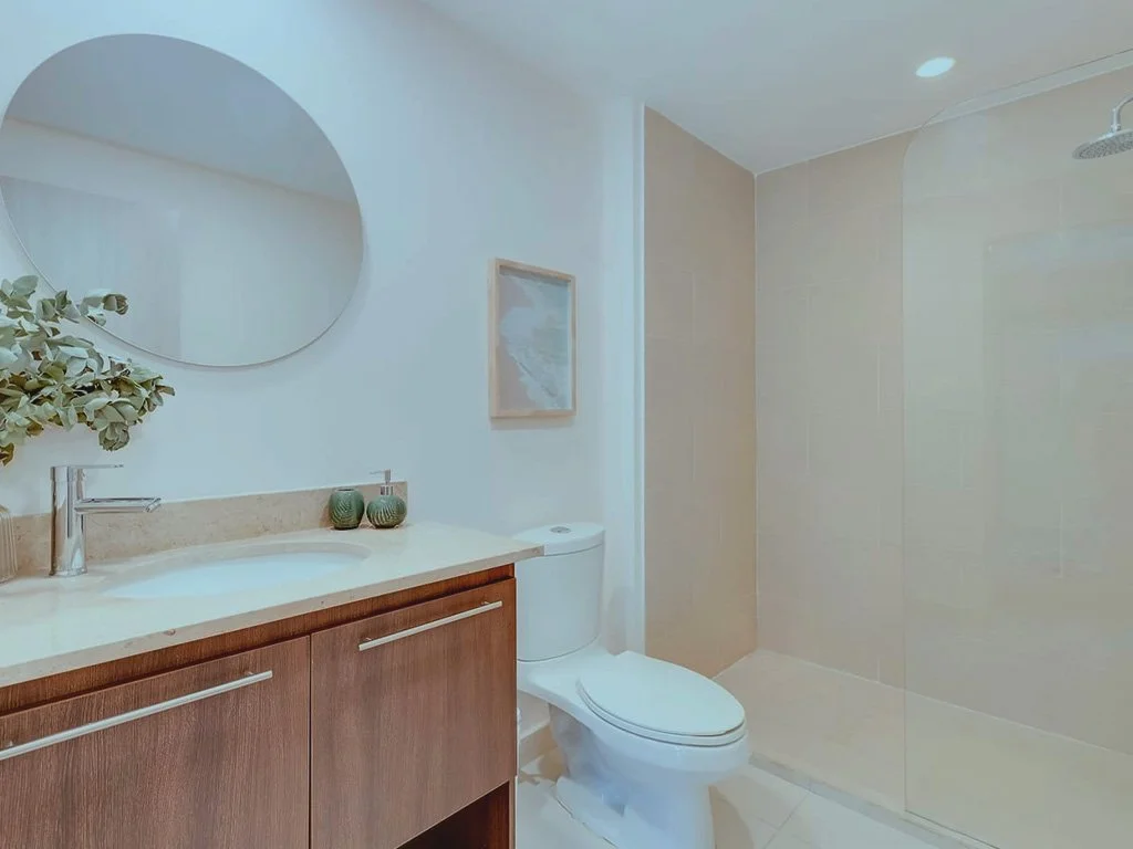 Contemporary full bathroom at Jacó Bay condominium featuring wooden vanity, large mirror, and walk-in shower.