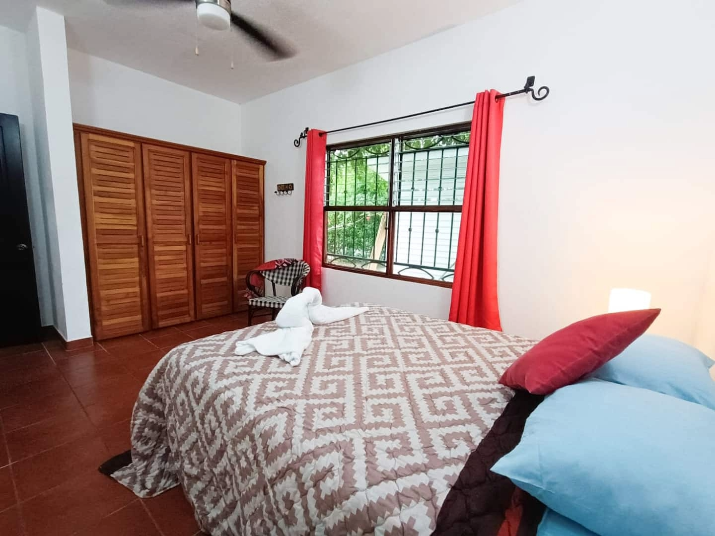 Cozy bedroom with double bed, wooden closet and window overlooking tropical garden at Mountain & Surf Oasis