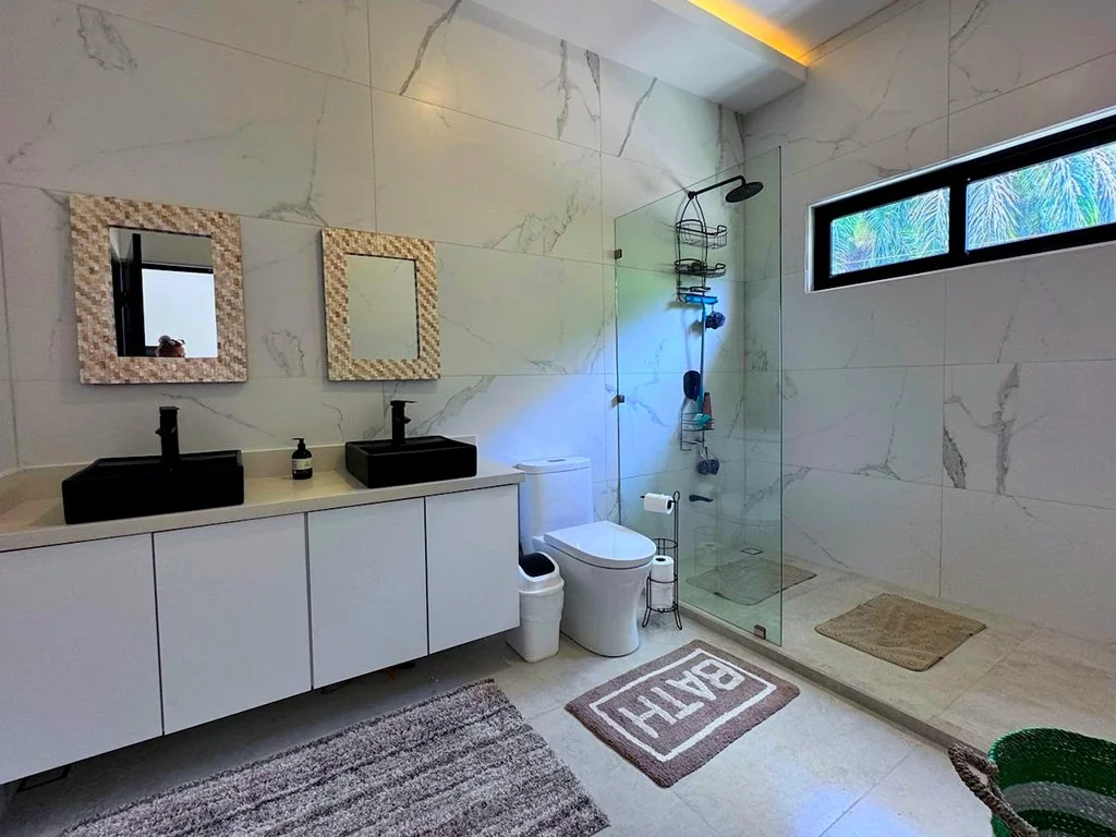Modern spacious bathroom with double vanity and glass shower at Casa LaVerde Ópera Salvaje in Costa Rica.