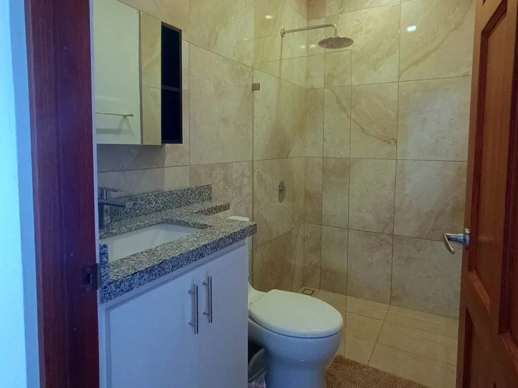 Contemporary bathroom with glass shower and granite countertop at Belford Apartments in Jacó Beach Front, Costa Rica.