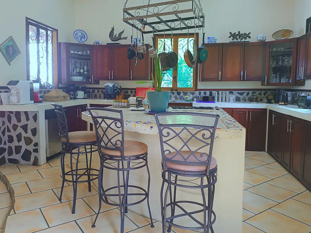 Spacious fully equipped kitchen with central island and rustic finishes at Jungle House Calle Hermosa.
