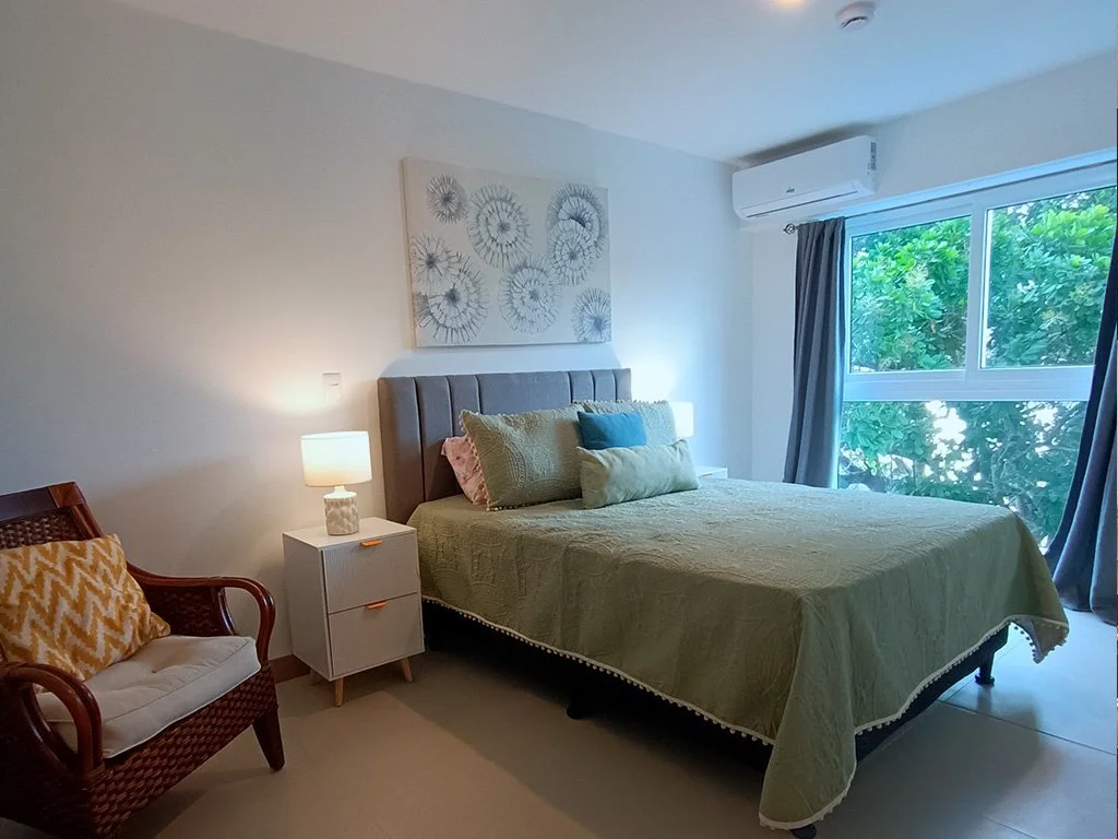 Modern master bedroom with natural light and comfortable bedding at Live Jacó condominium in Jacó, Costa Rica.