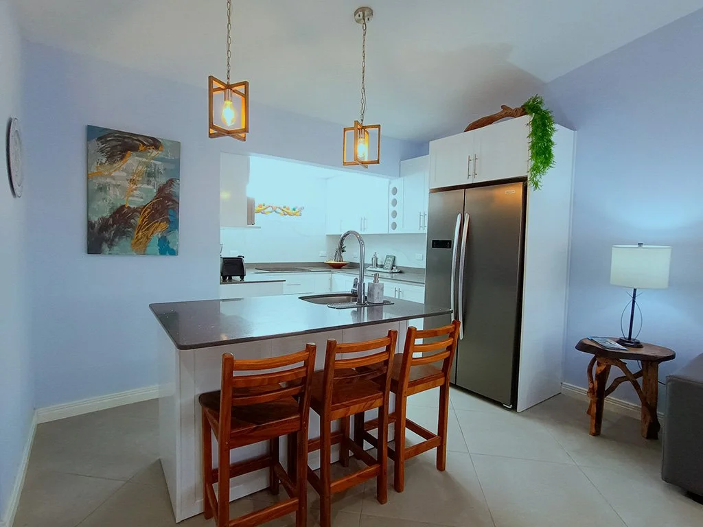 Bright modern kitchen with island seating at Beach apartment COCO 49 vacation rental in Jacó, Costa Rica.