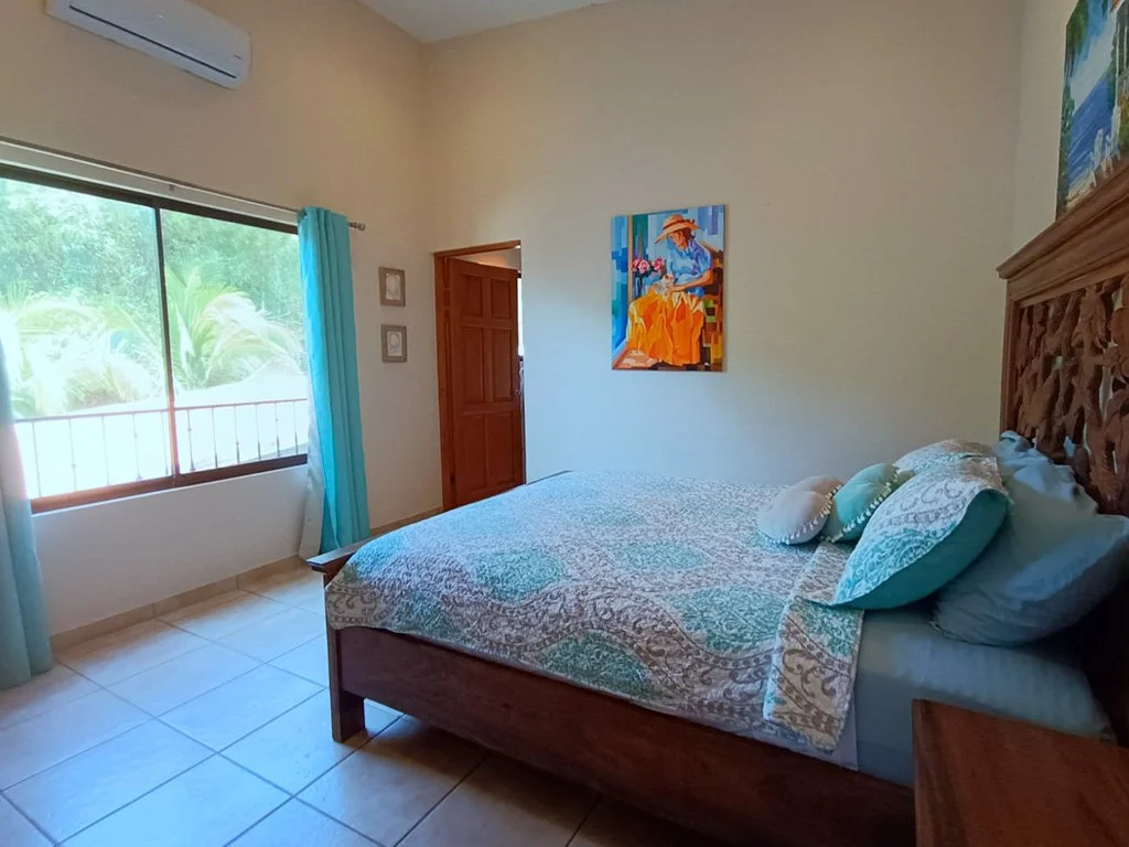 Bedroom in the upper unit of Hermosa Duplex Playa Hermosa featuring a double bed, air conditioning, natural light, and tropical view.