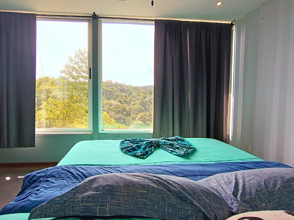 Bedroom with large windows overlooking the mountains and tropical landscape at Container House in Cerro Fresco, Costa Rica.