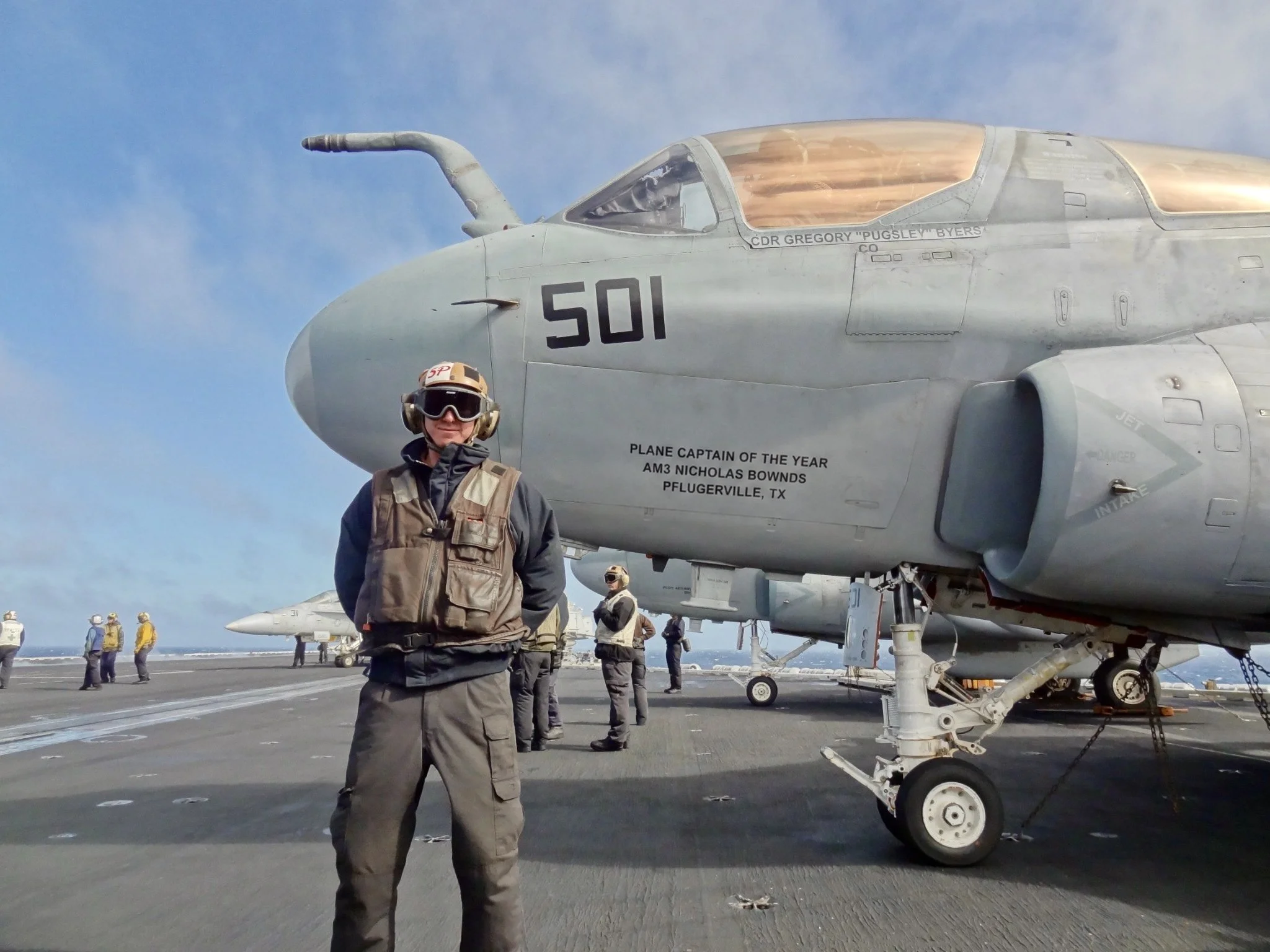 Nick Bownds standing beside an EA-6B Prowler aboard an aircraft carrier