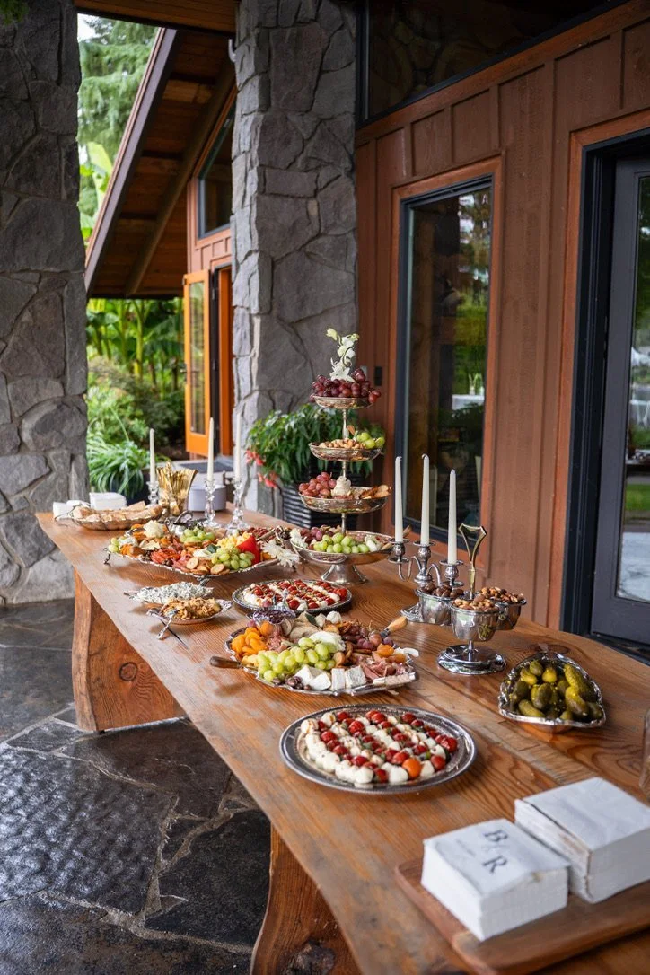 An outdoor grazing table with silver tiers and taper candles