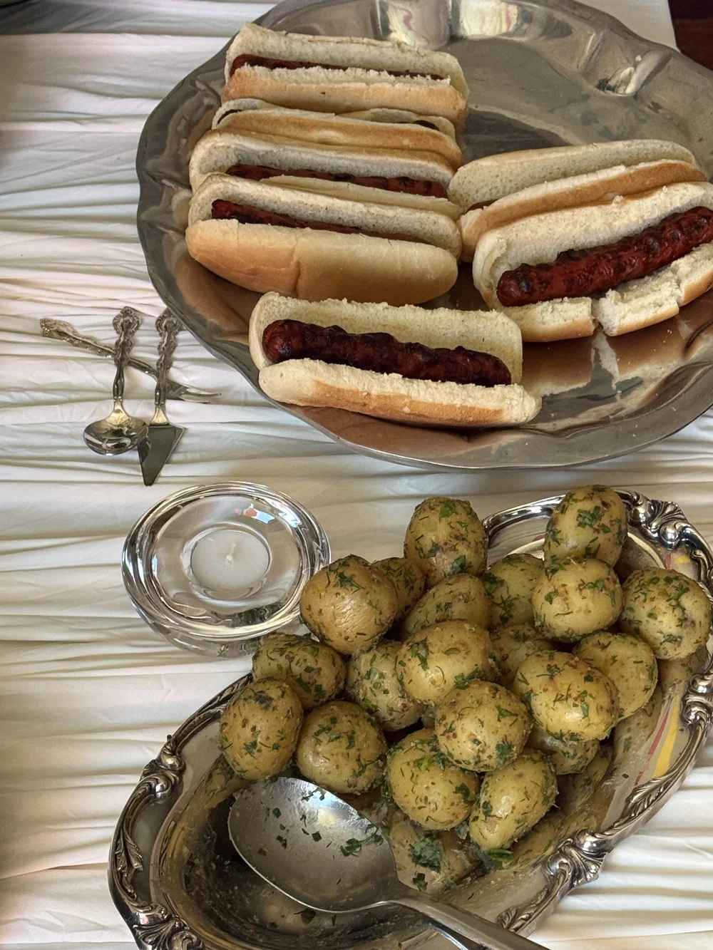 Hot dogs and herbed potatoes served on vintage silver