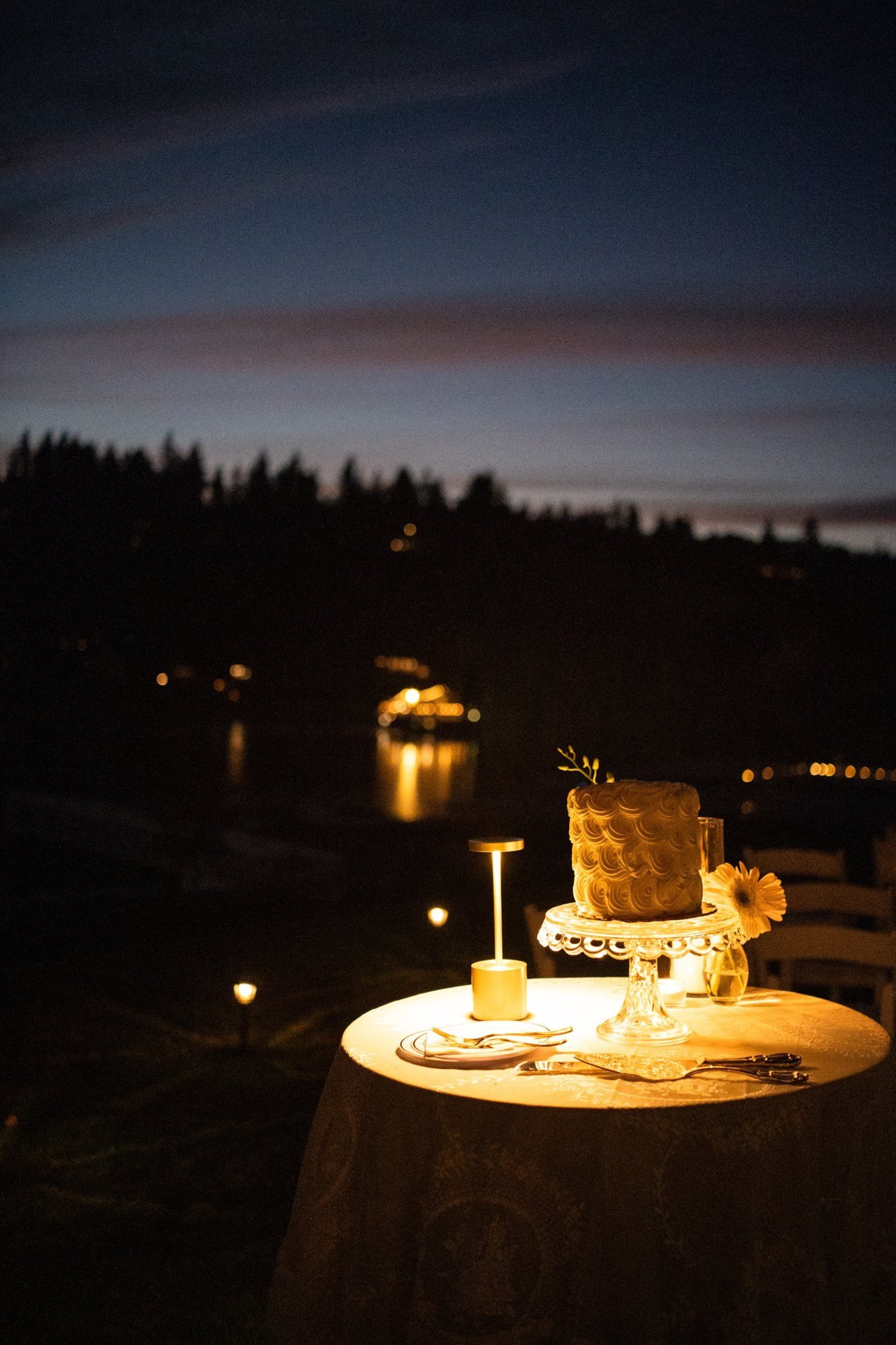 A candlelit cake table overlooking the lake at night