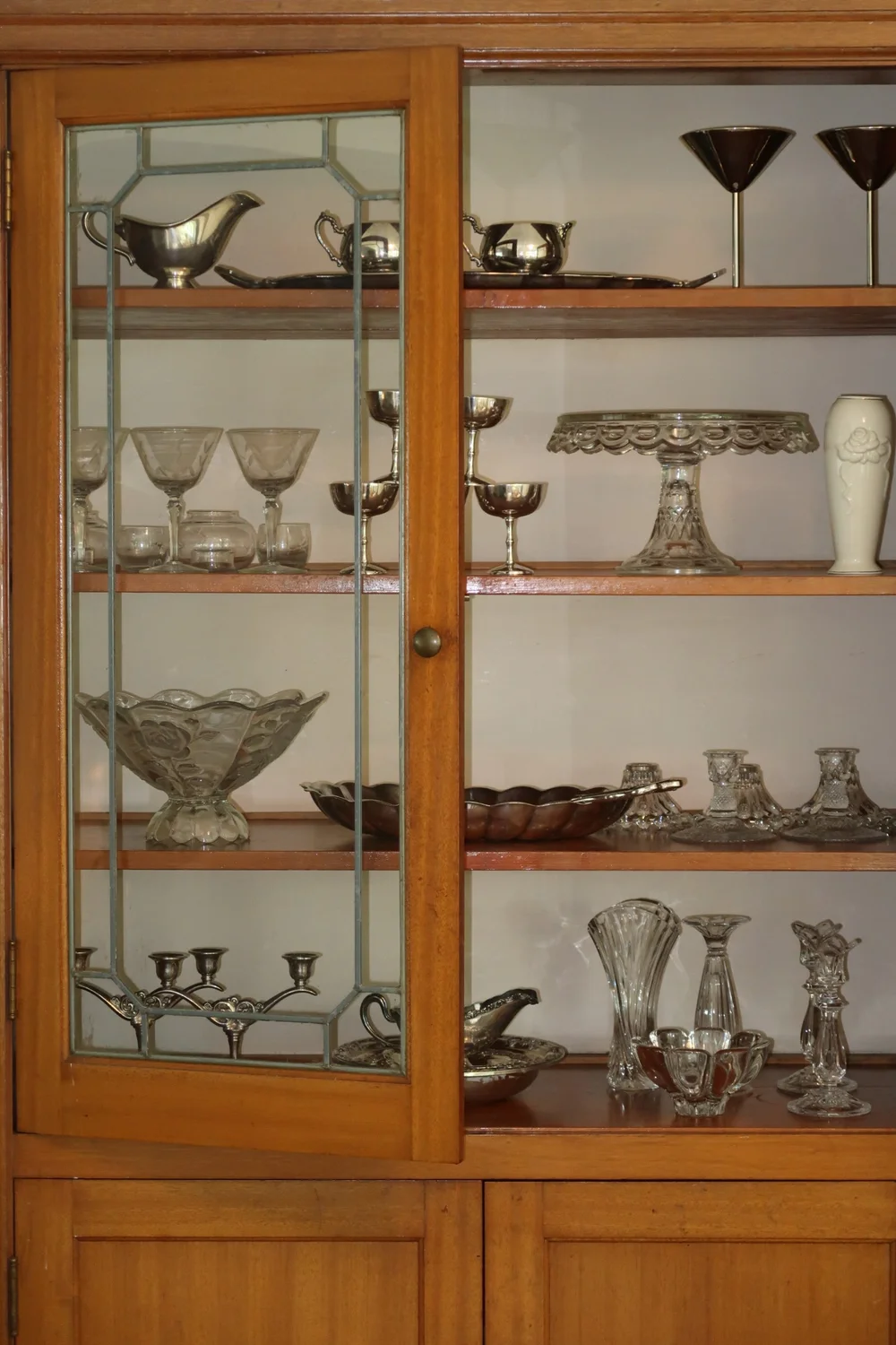 A vintage cabinet full of Era silver and glassware