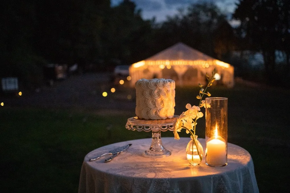 A rosette cake on a glass stand at dusk