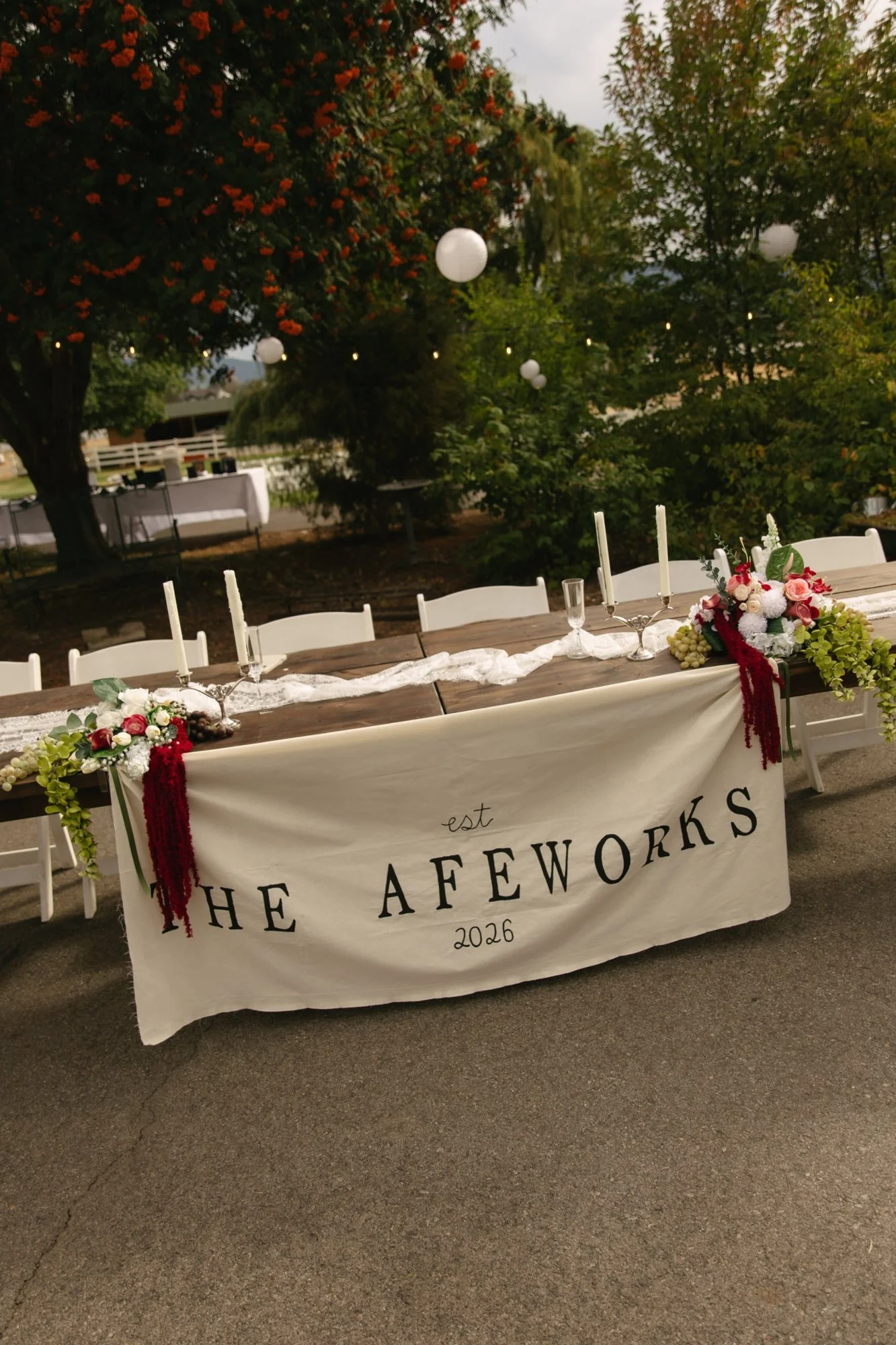 A head table with lace runner, candelabras and a custom banner
