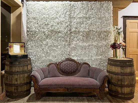 Vintage Maroon Couch styled with a white floral wall and whiskey barrels.
