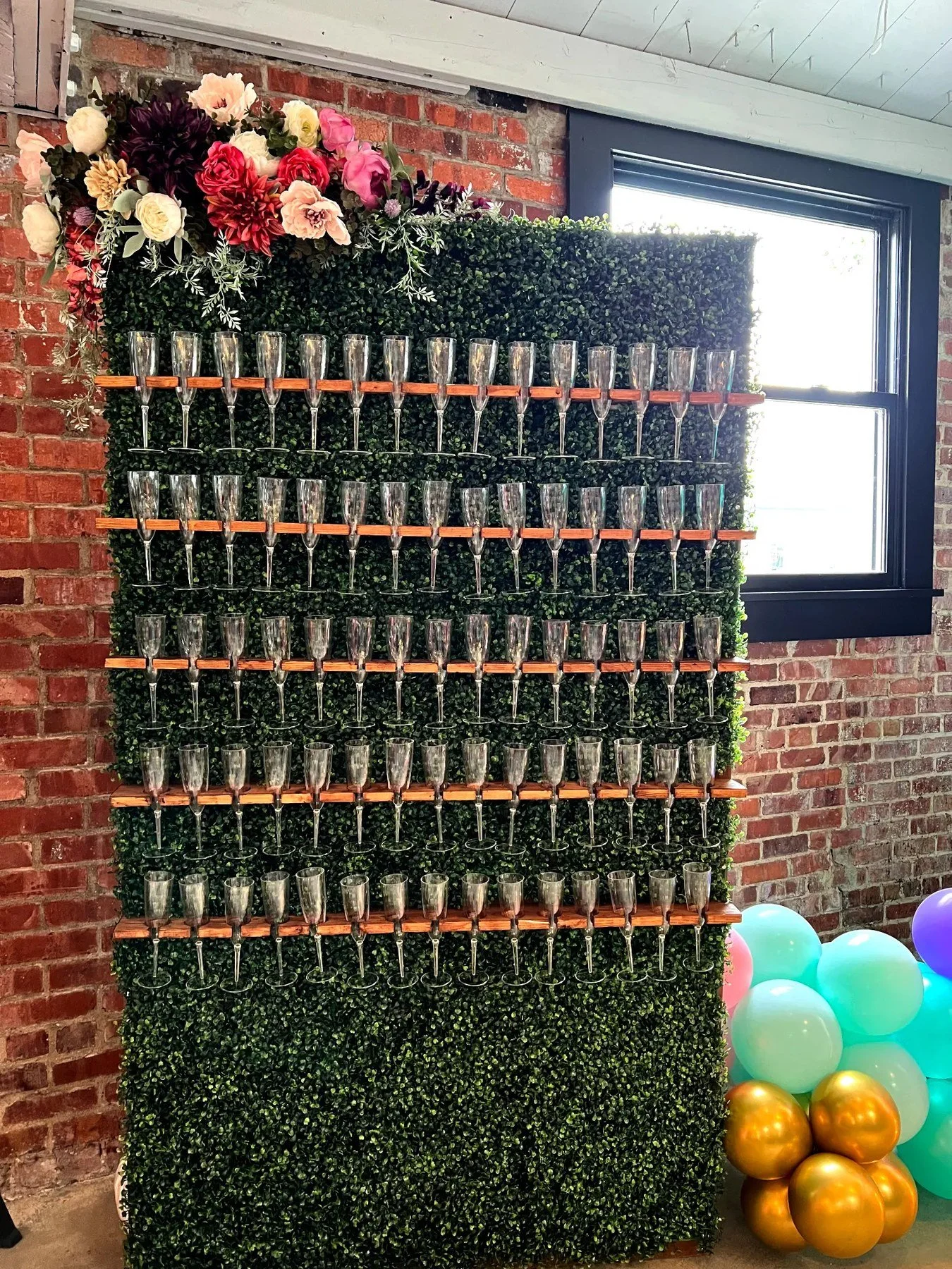 Champagne Wall with champagne flutes, greenery and floral accents.