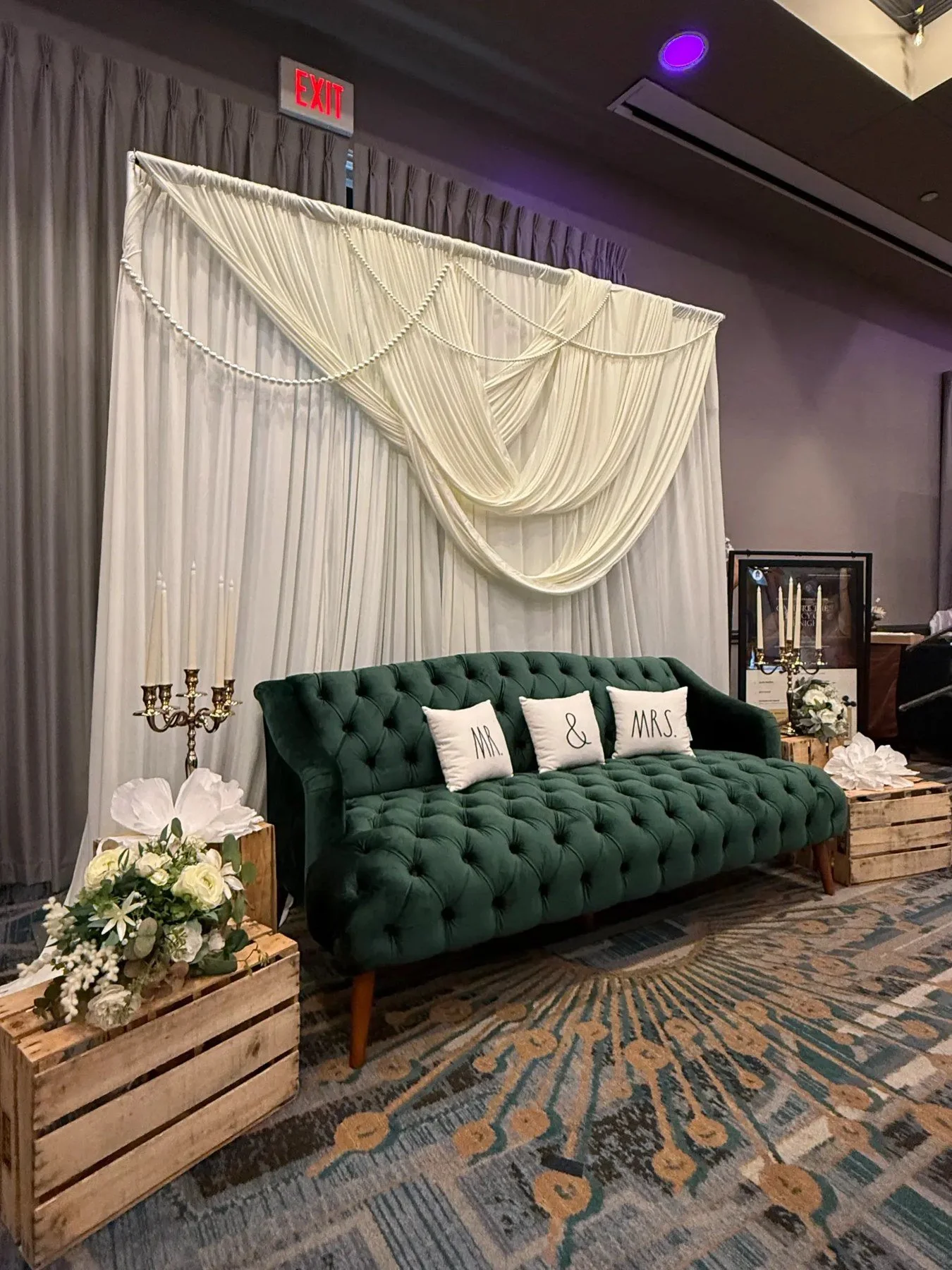Green modern couch with an ivory drape backdrop.