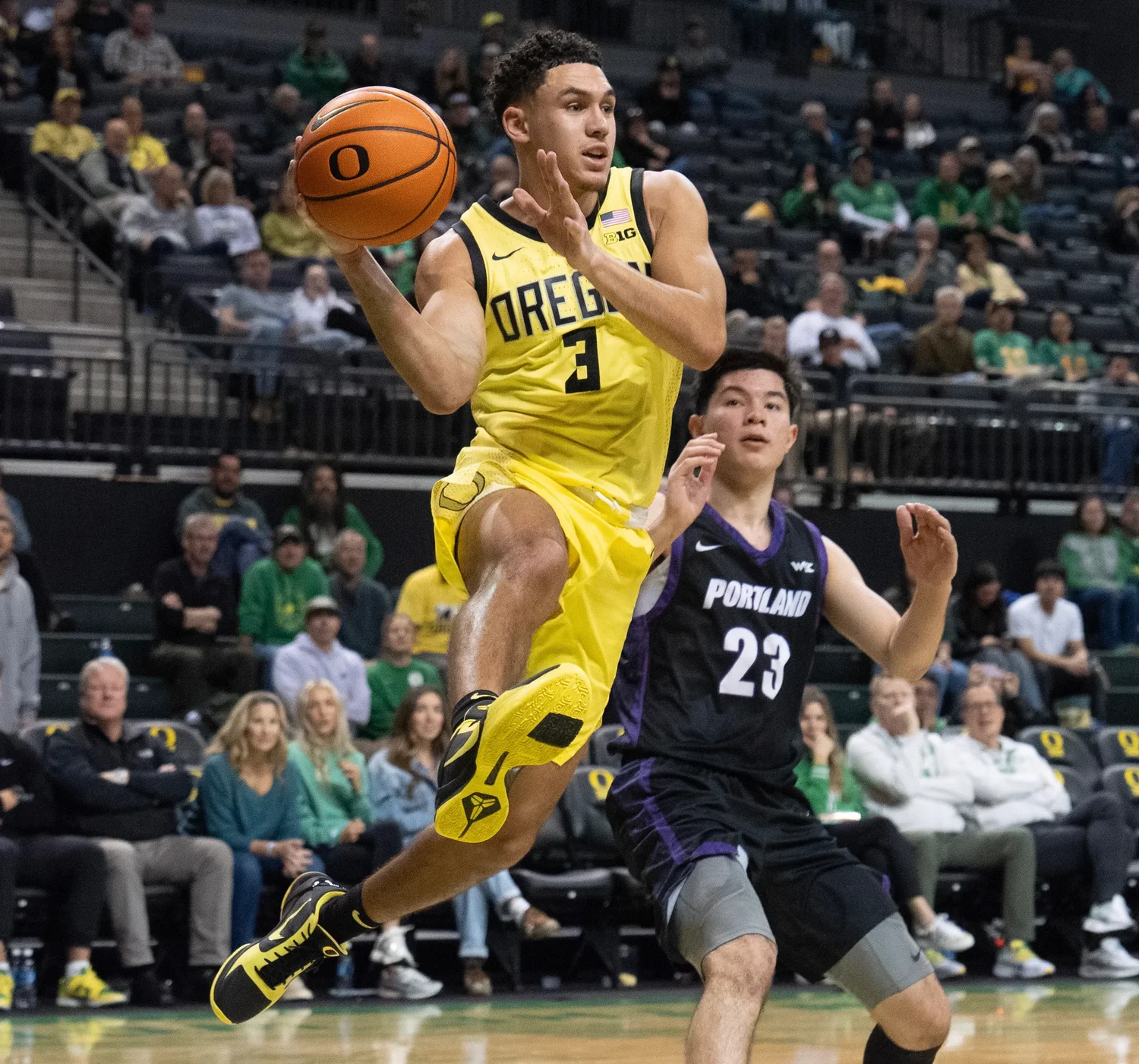 Oregon basketball player drives toward the basket against a defender.