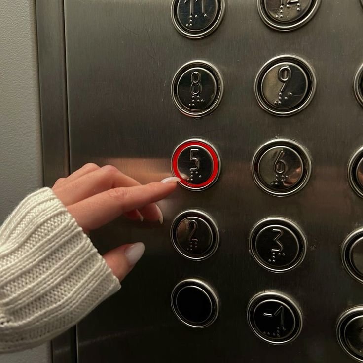 A hand pressing the fifth-floor button in an elevator