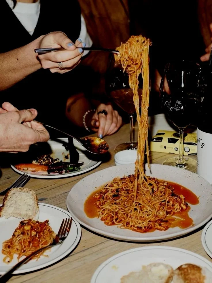 Spaghetti lifted from the plate at a candlelit table