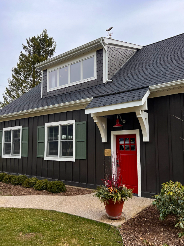 Exterior remodel with dark custom color James Hardie board and batten siding and a red front door