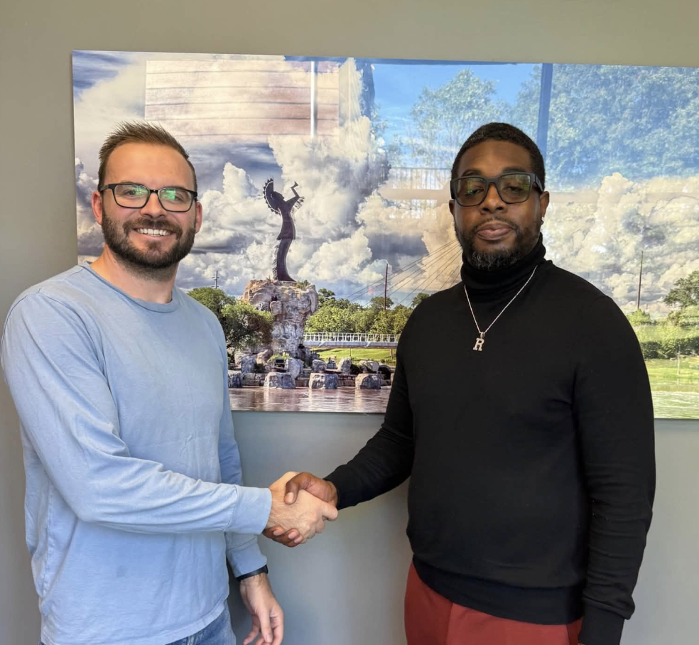 Micah Harder of Seek First Capital shaking hands with a Wichita real estate investor in front of the Keeper of the Plains