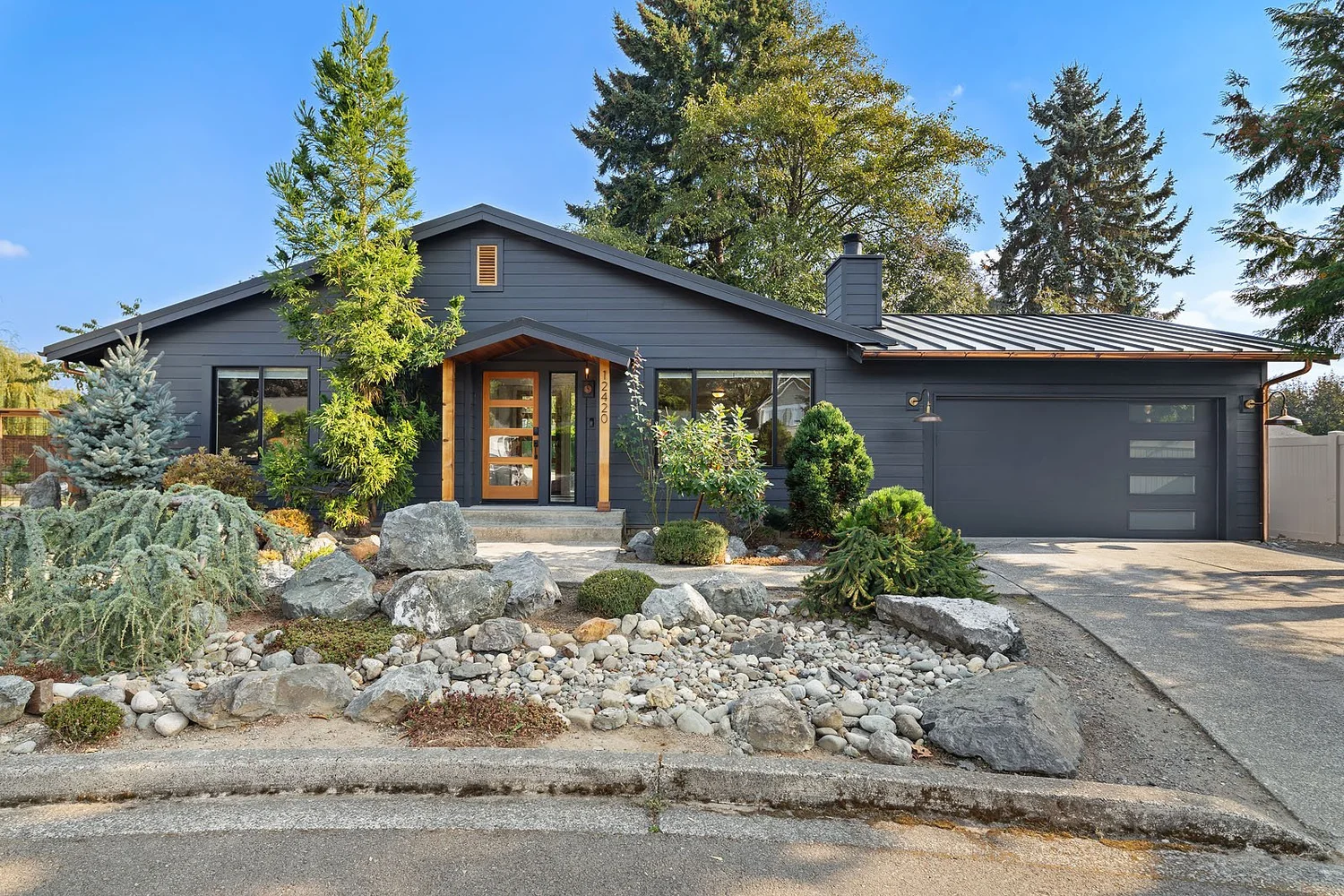 Remodeled home exterior with charcoal siding, cedar entry, and landscaped front garden