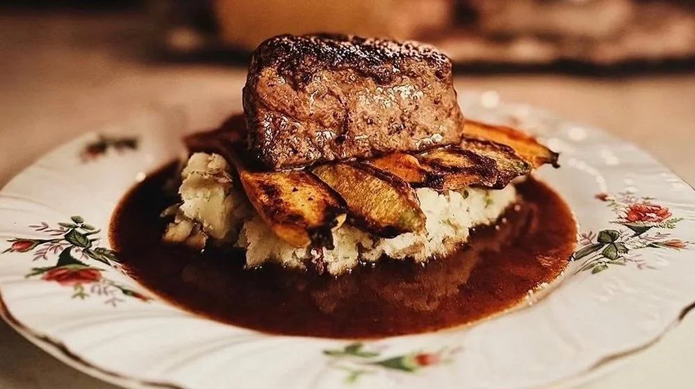 Seared filet mignon served over mashed potatoes with roasted vegetables and a rich demi-glace sauce at 205 Dry.