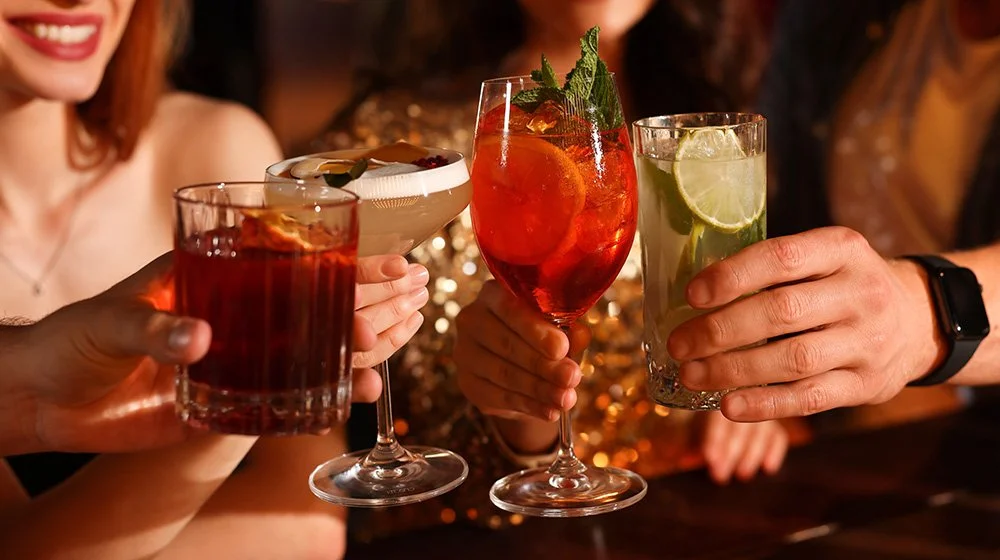 Friends raising handcrafted cocktails in a warm, intimate speakeasy setting.