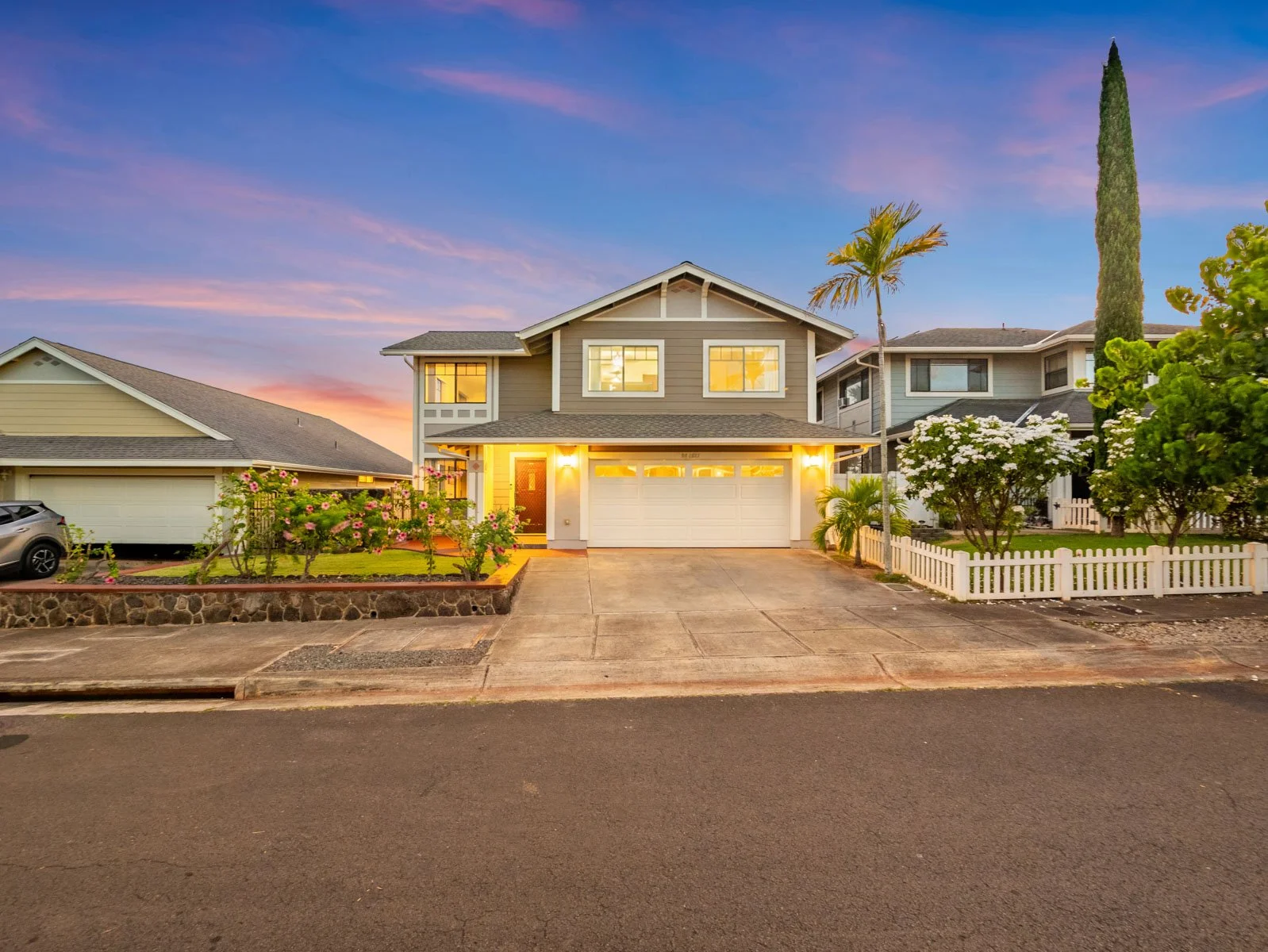 Twilight front exterior with lit windows, two car garage and wide driveway