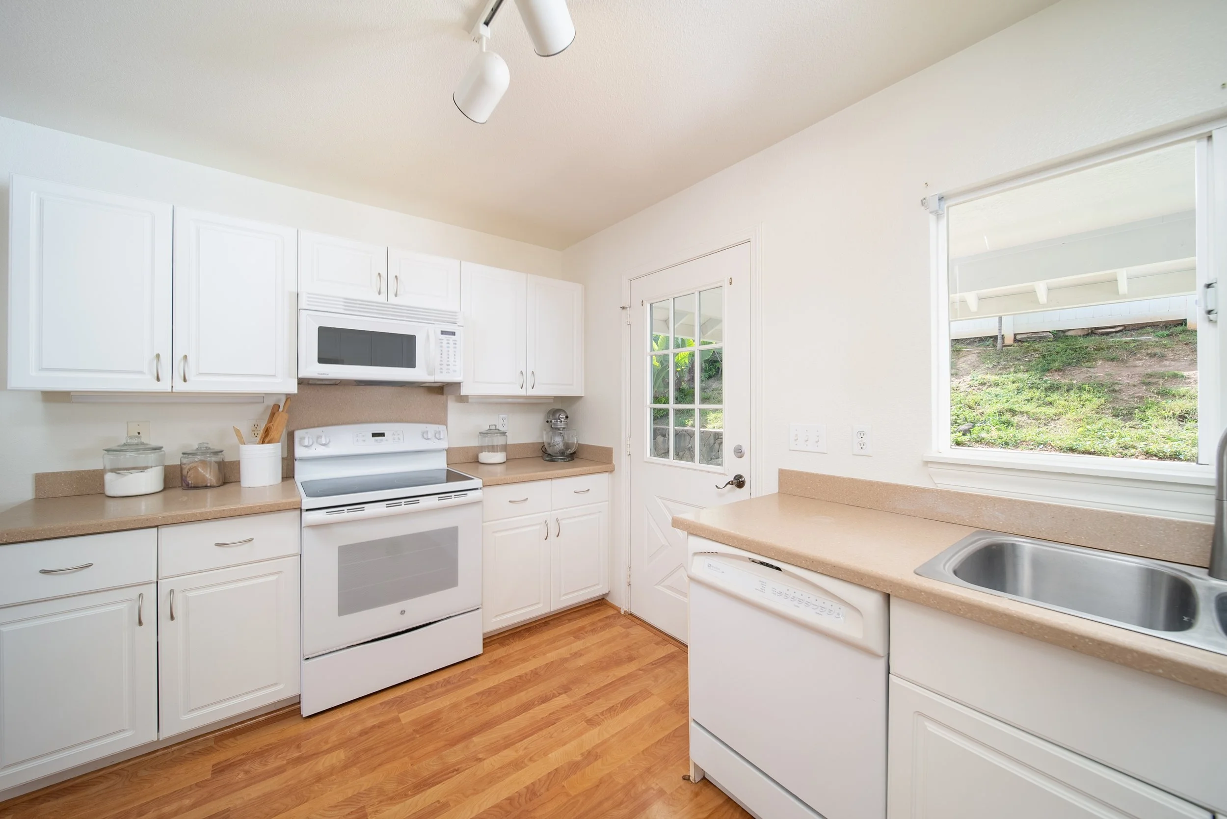 Kitchen with white cabinetry, electric range and garden window above the sink