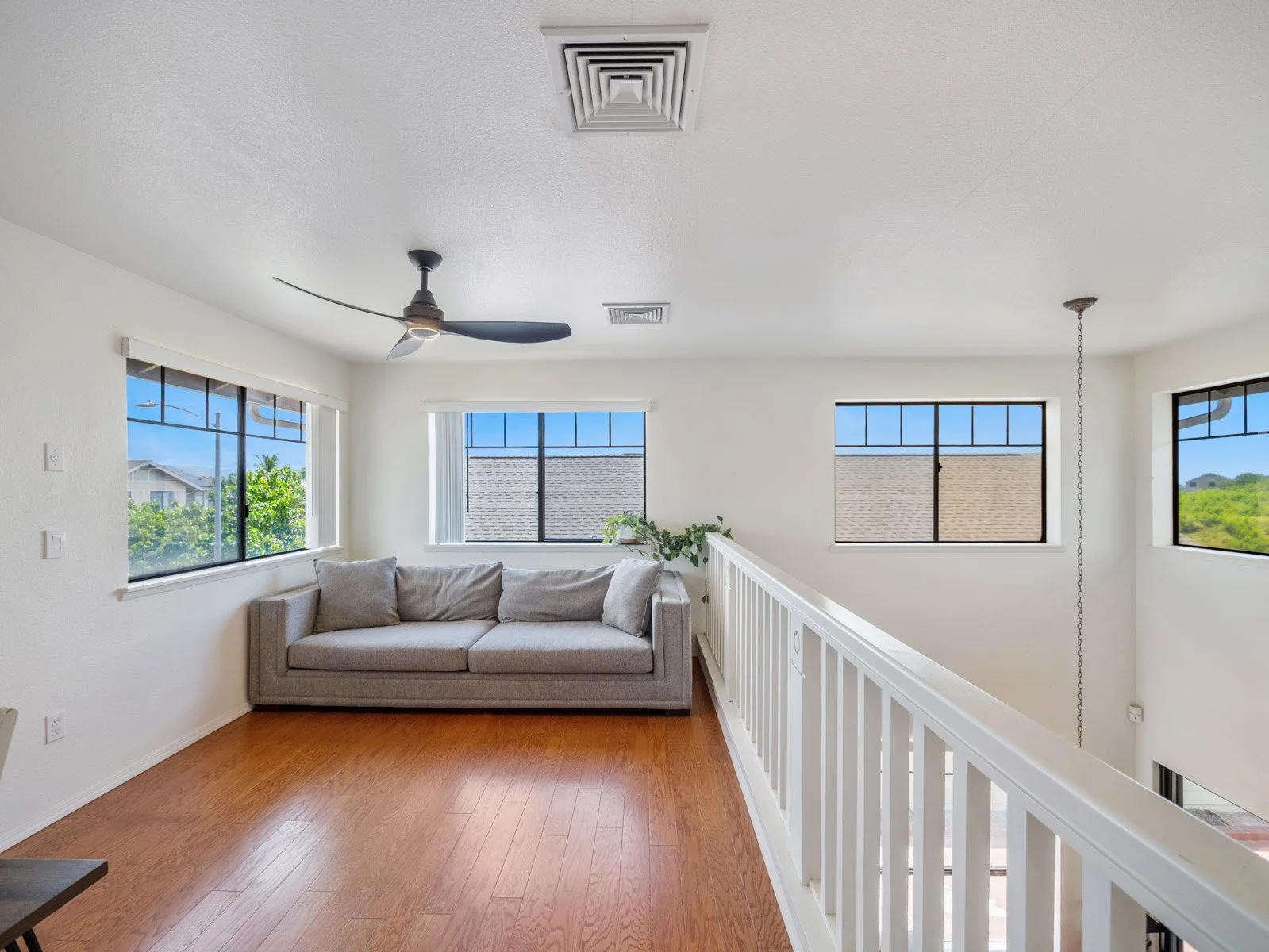 Upstairs loft with sofa, open railing and windows on three sides
